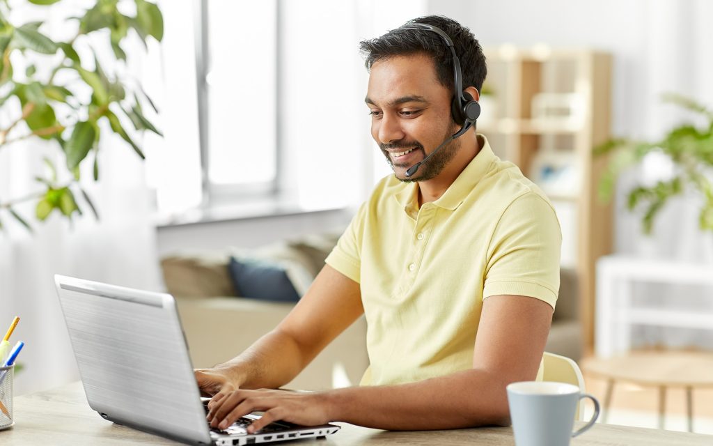 Technology and people concept - happy smiling man with headset and laptop computer